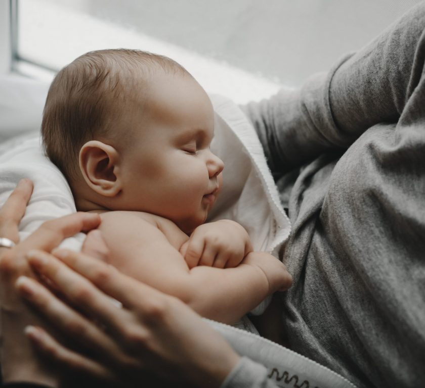 Charming newborn boy sleeps on mother's arms